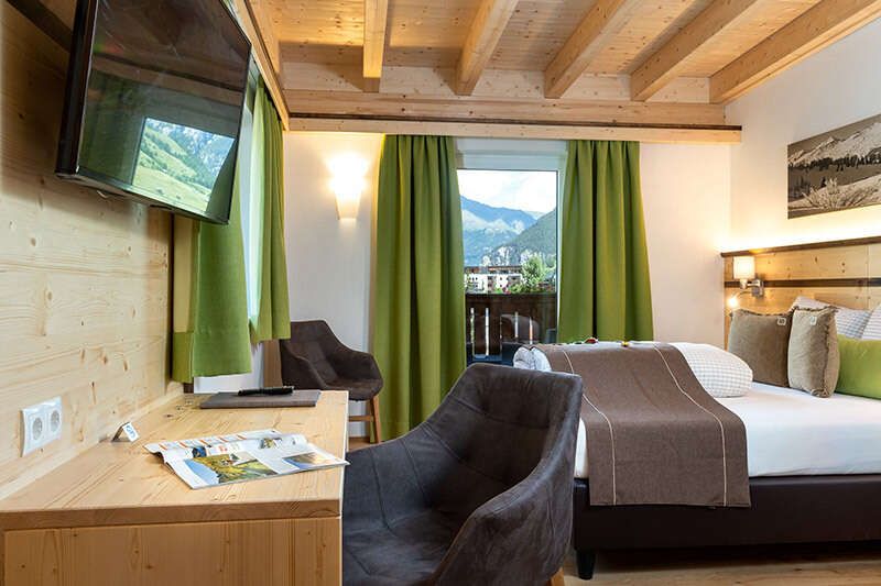 Doppelbett, Schreibtisch und Balkon im Panoramazimmer im Hotel Schlossberg Nauders