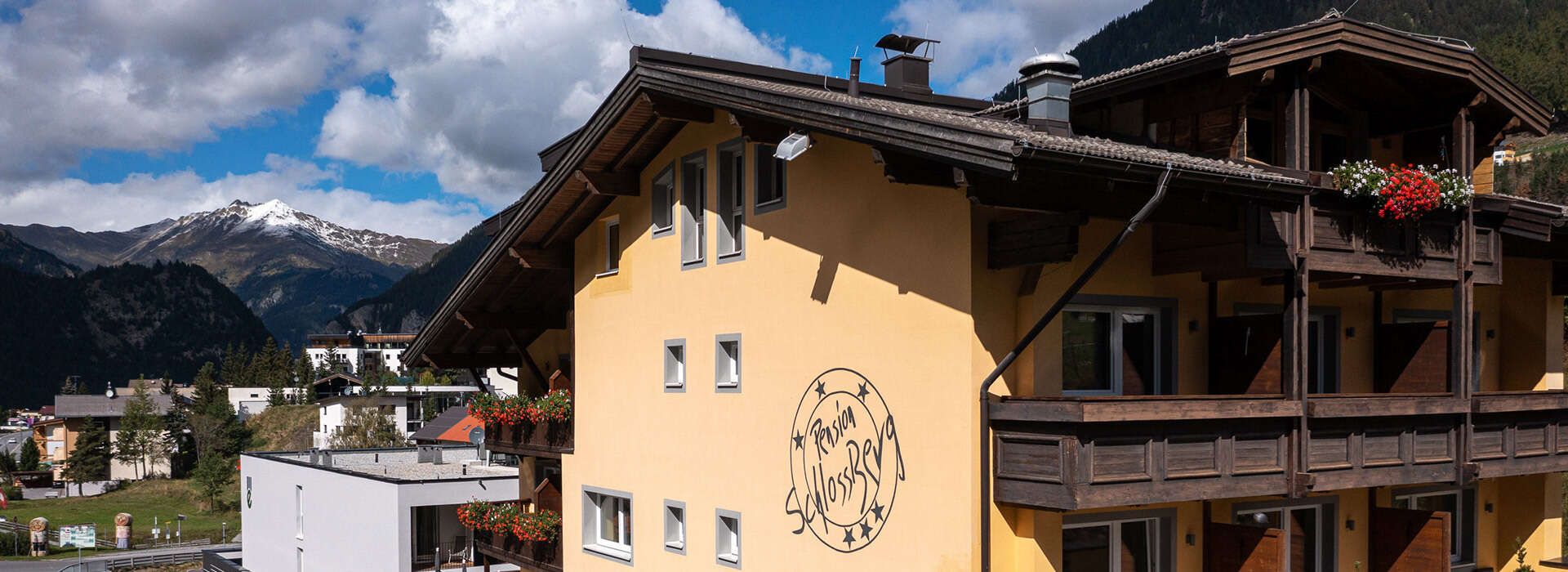 Hotel Schlossberg Hausansicht im Sommer mit Logo